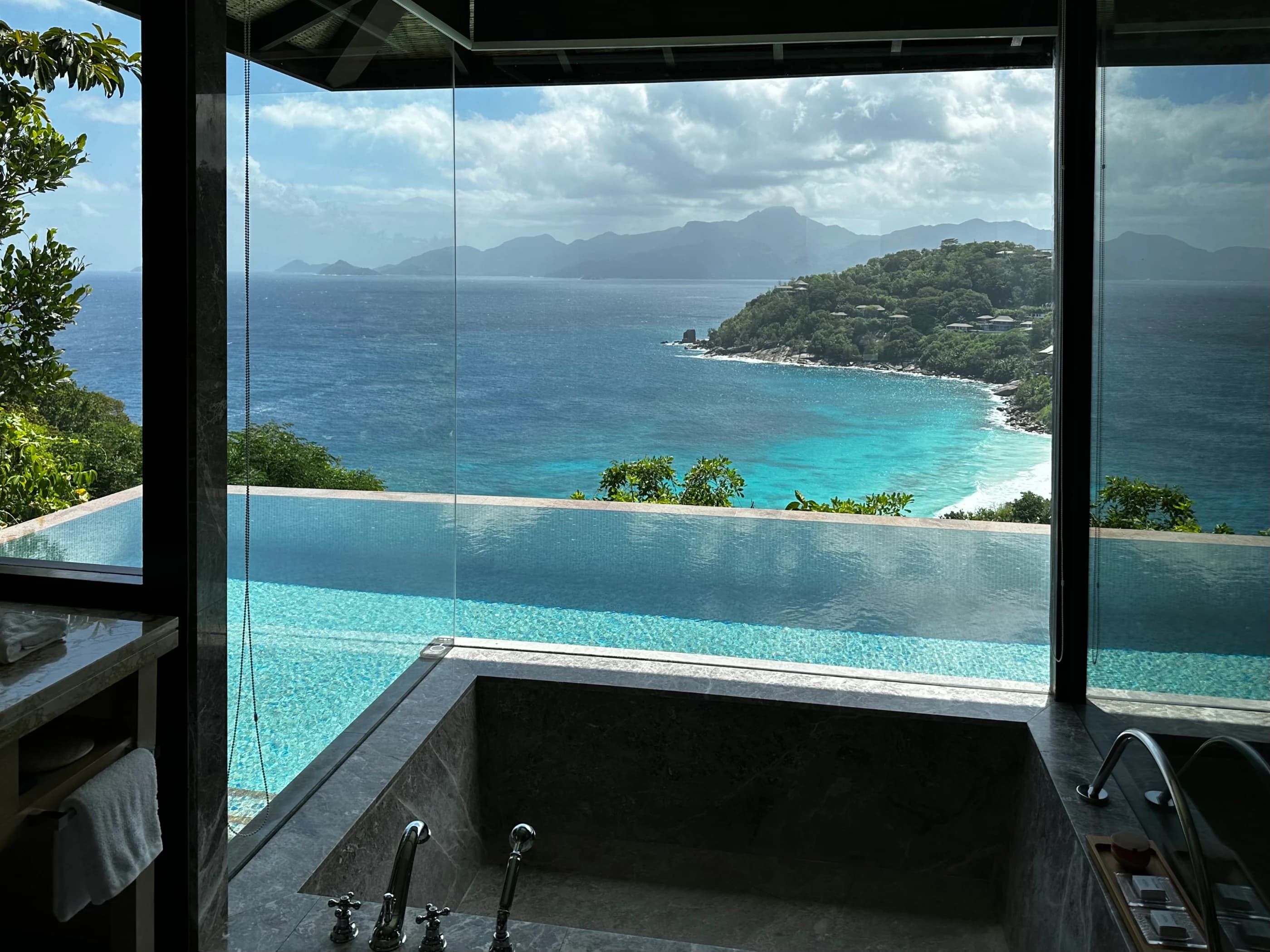 An infinity pool and open window overlooking a quiet island bay.